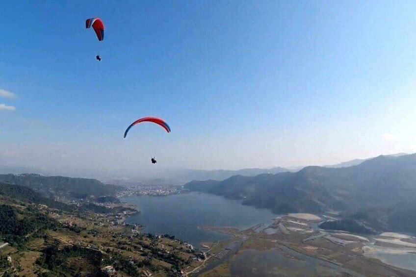 Una persona practica paracaidismo sobre un valle con un lago y montañas al fondo. 5