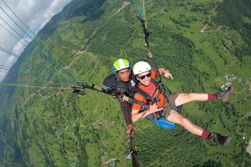 Two people paragliding with a mountainous landscape in the background. 3
