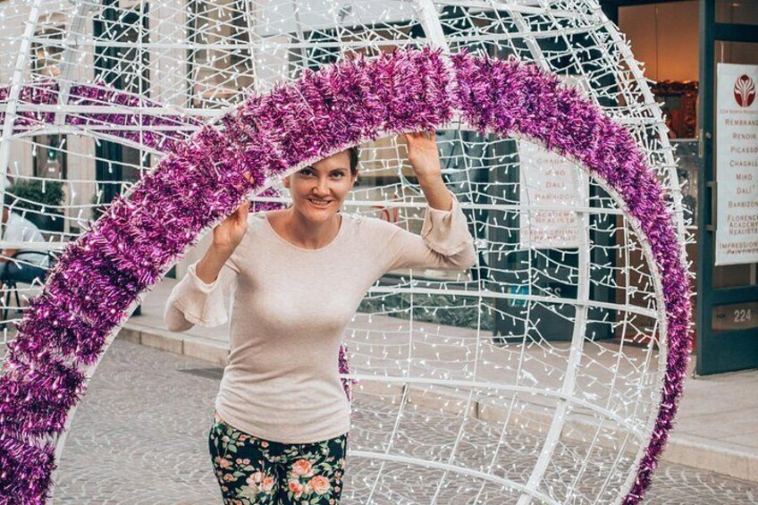 A person standing in front of a decorative structure with a purple tinsel arch. 2