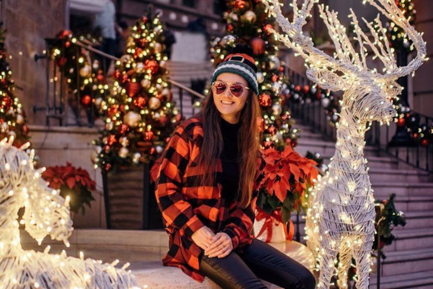 Une personne assise devant un sapin de Noël décoré, illuminé et orné de guirlandes. 1