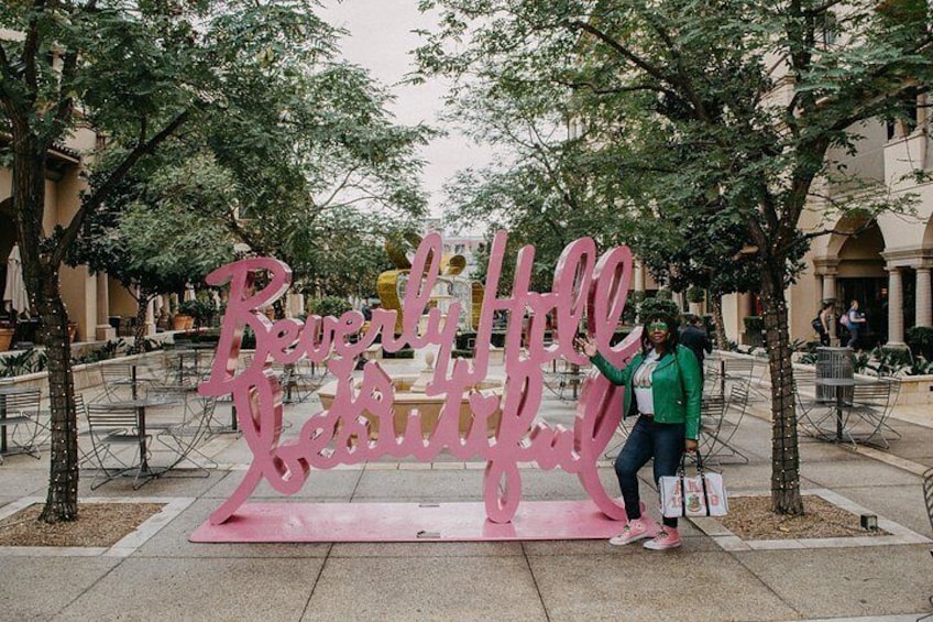 A pink sign with the text 'Reverly Hill' in a public outdoor area with trees and benches. 4
