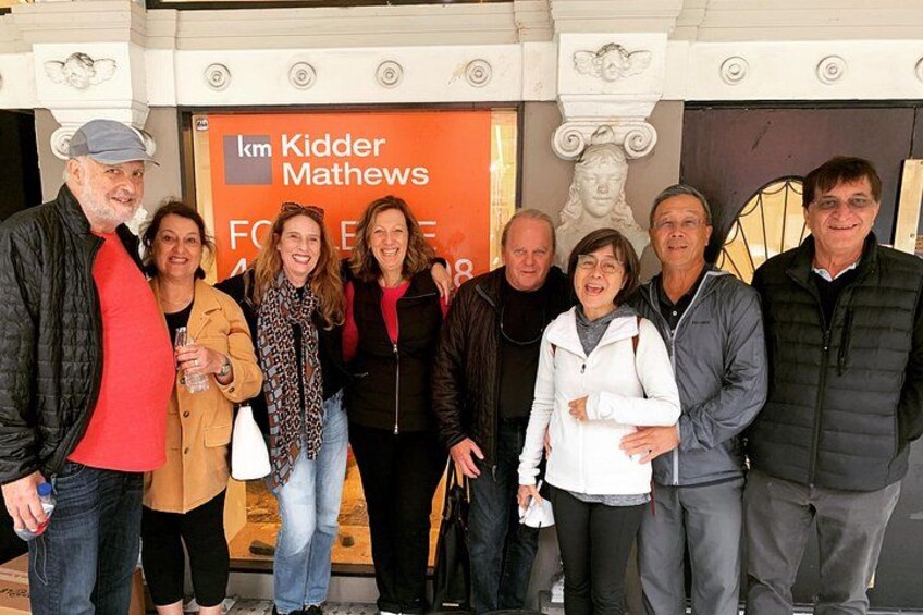 A group of people standing in front of a building with a sign that reads 'km Kidder Mathews.' 2