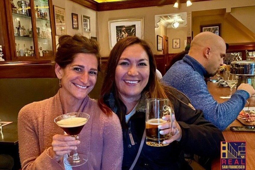 Three people sitting at a bar with drinks. 1