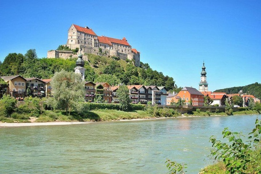 A river with a castle on a hill, a church with a tower, and houses along the riverbank. 3