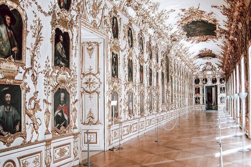 An ornate corridor with elaborate wall decorations and framed portraits. 2