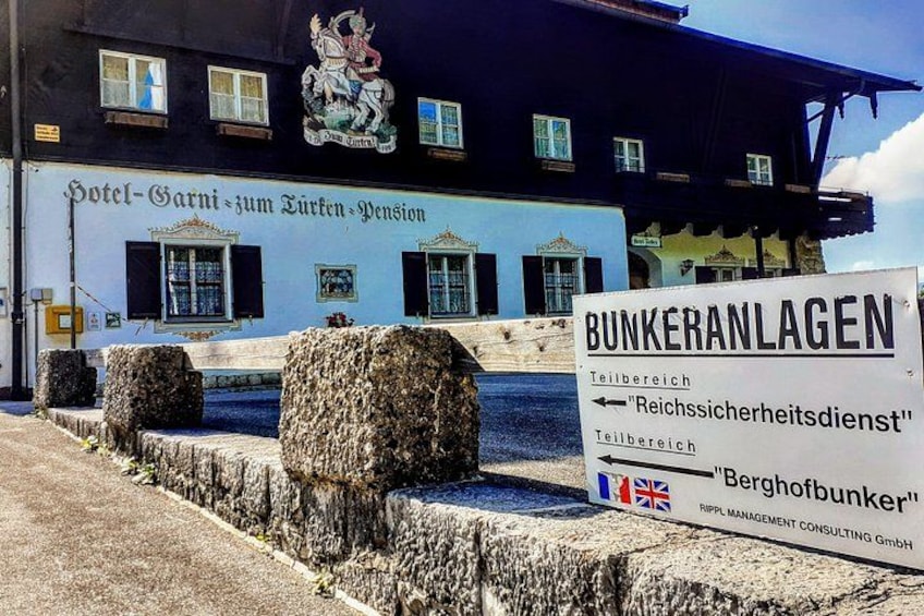 A building with a sign for 'Hotel-Garni- Zum Eichen-Pension' and another sign for 'Bunkeranlagen' with flags. 4