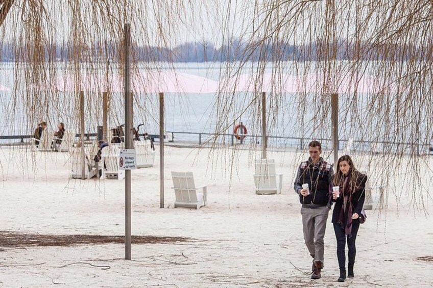 Een besneeid strand met mensen die wandelen, een reddingsboei en een bord. 3