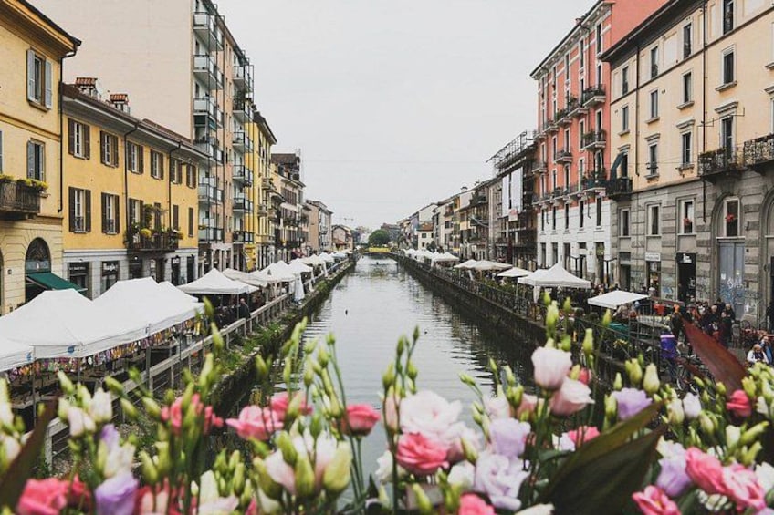 En kanal som kantas av färgglada byggnader och blomsterstånd. 1