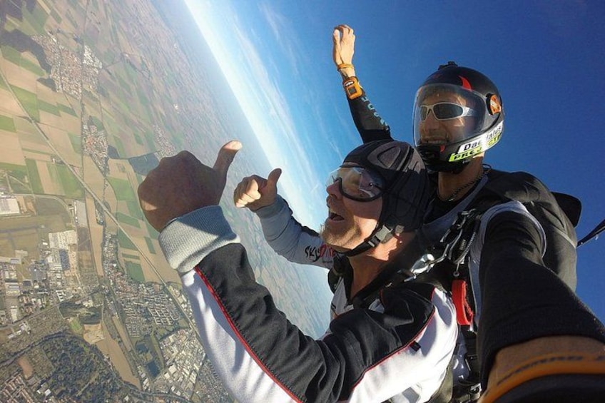 Zwei Fallschirmspringer im freien Fall mit einer Landschaft darunter. 1