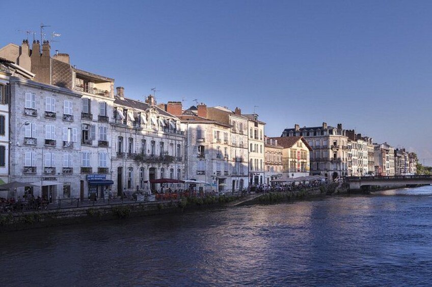 Een waterkantpromenade met historische gebouwen, een brug en een rustig waterlichaam. 2