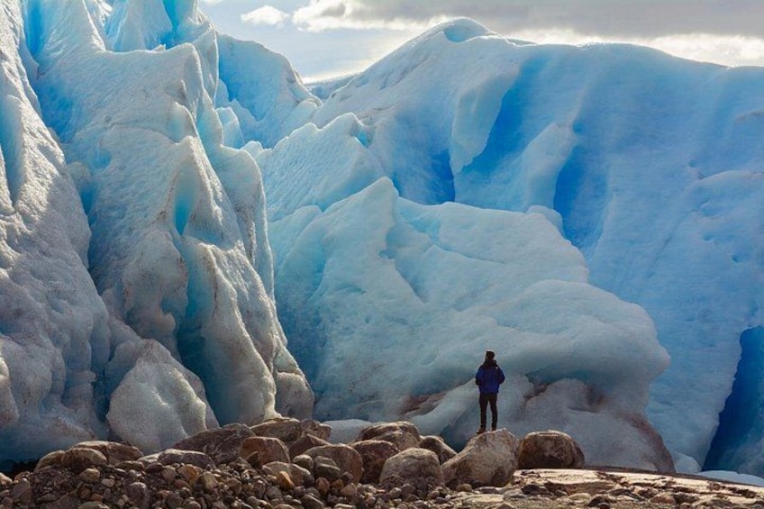 A glacier with a person standing on a rocky outcrop. 1