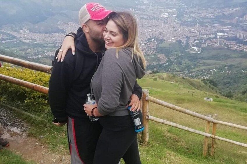 A couple embracing on a hillside with a cityscape in the background. 5