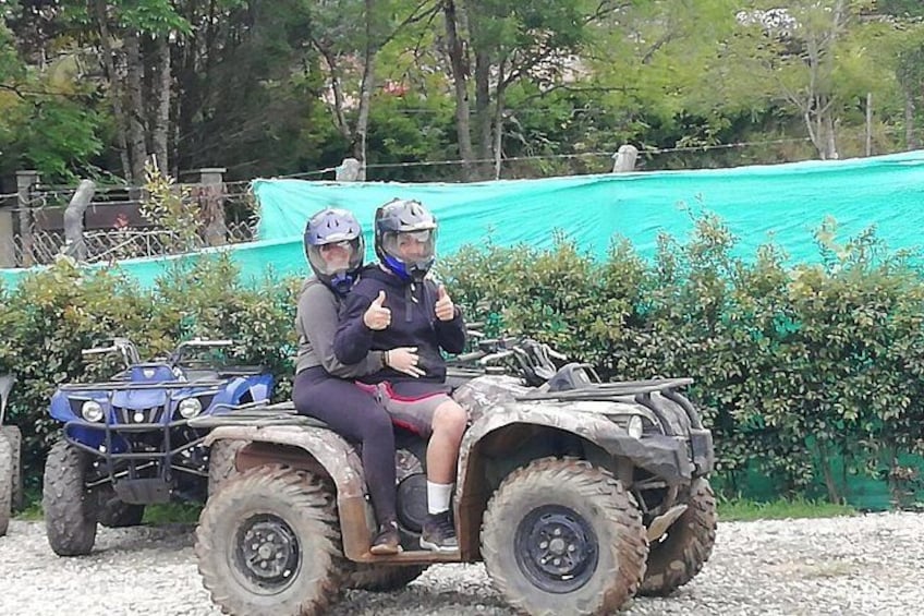 Two people on an ATV with a blue vehicle in the background. 4