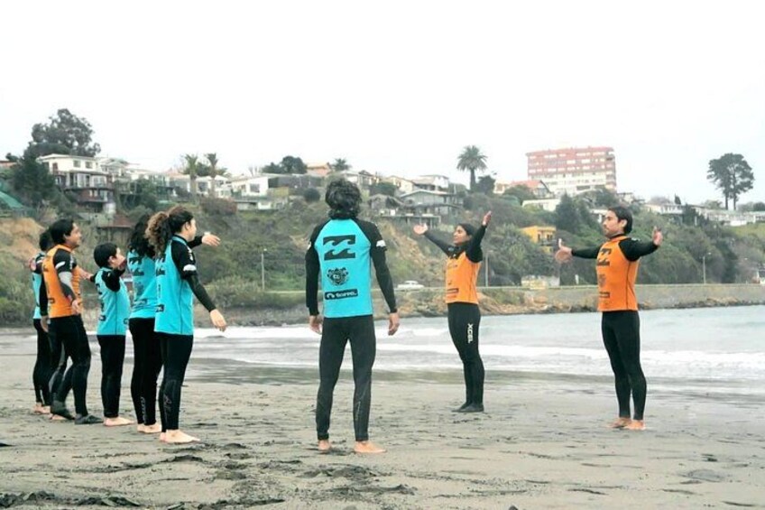 Eine Gruppe Menschen am Strand, einige tragen Orange, andere Blau, mit einem Gebäude im Hintergrund. 1