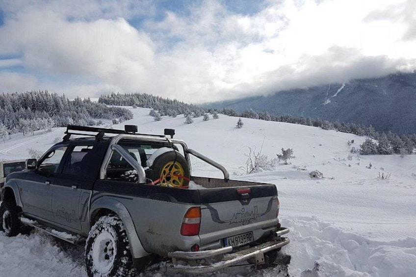 En silverfärgad pickup-truck parkerad på en snötäckt sluttning med ett berg i bakgrunden. 1