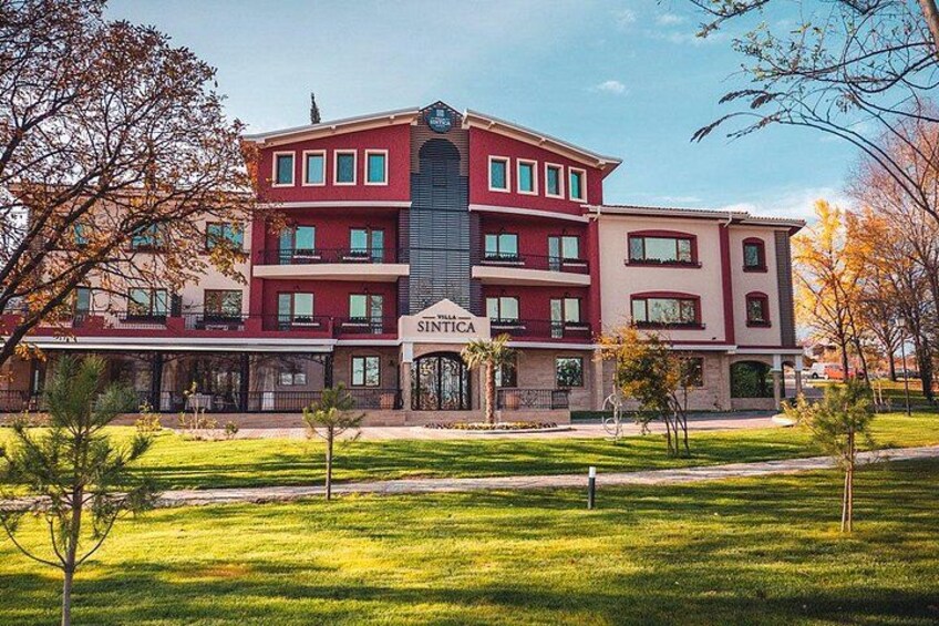 A multi-story building with a red facade and a sign that reads 'Villa Sintica.' 1