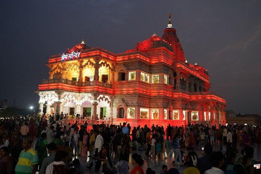 A large, ornate building with intricate architecture, a crowd of people gathered in front, and a prominent sign with text. 3