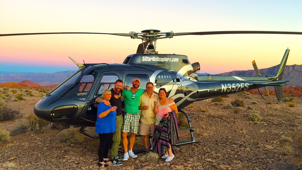 Group of passengers gather outside of helicopter on the edge of the Grand Canyon