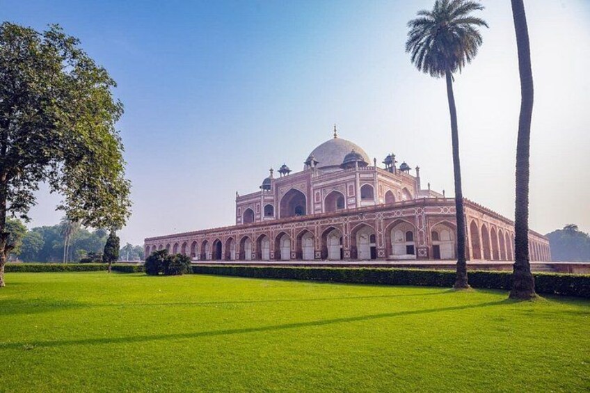 A large, historic building with domes and arches, surrounded by a well-maintained lawn and palm trees. 2