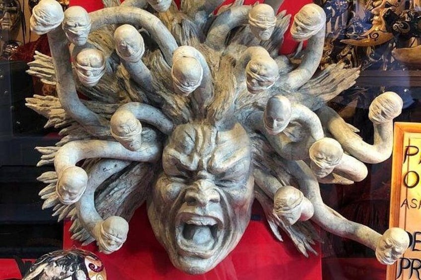 A sculpture with multiple faces and hands. 5