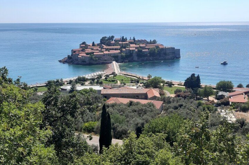 A coastal town with a prominent castle on a hill, a beach, and lush greenery. 1