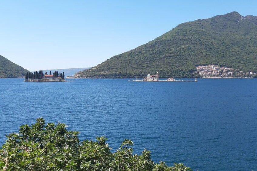 A calm lake with a small island, a mountain in the background, and a clear sky. 4