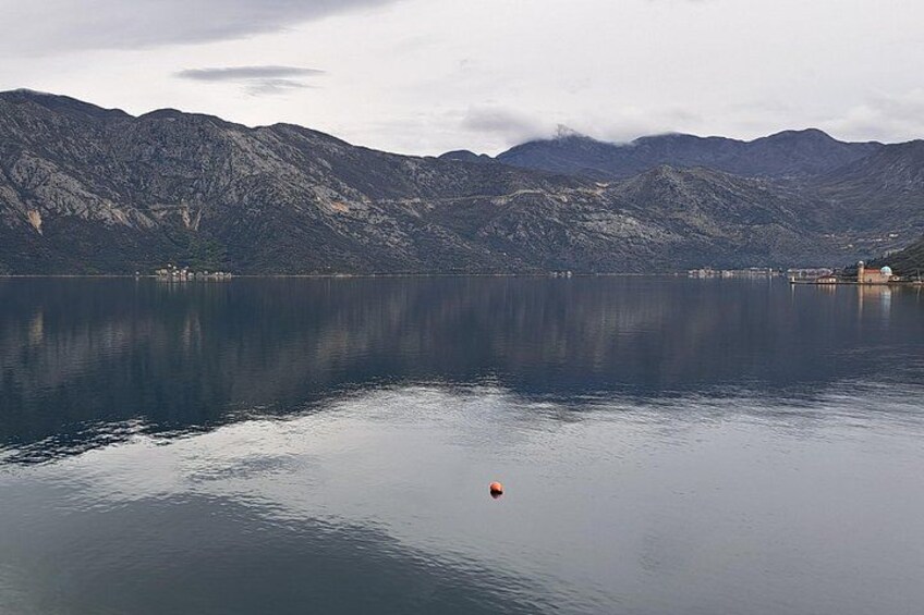 Een rustig meer met bergen op de achtergrond en een boei in het water. 5