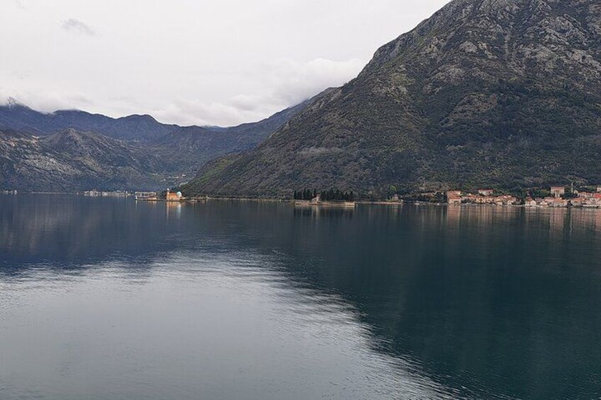 Un lago tranquilo con una montaña al fondo y un pequeño asentamiento a orillas del agua. 5