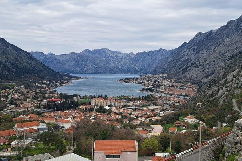 A coastal town with mountains in the background, a body of water, and a bridge. 4