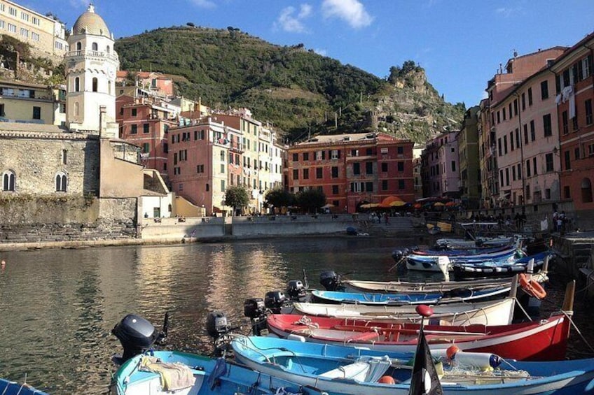 Un pueblo costero con barcos amarrados a lo largo del muelle, edificios históricos y una colina al fondo. 3