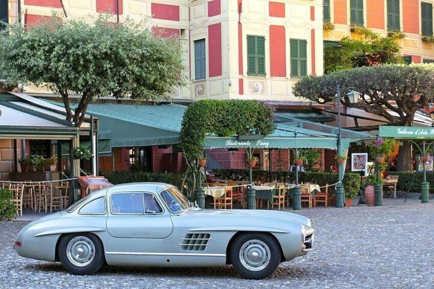 Un coche antiguo estacionado frente a un café con terraza. 4
