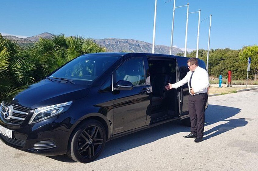 A black van parked on a road with mountains in the background. 3