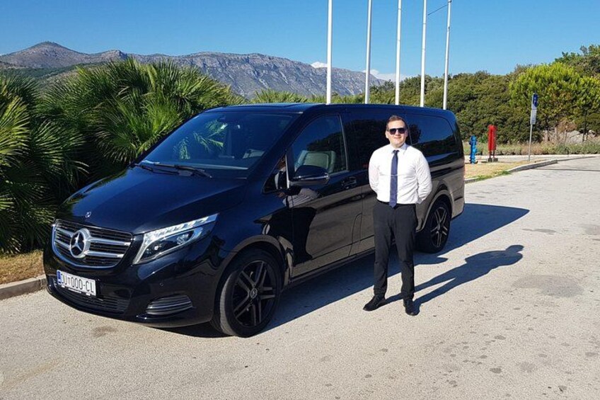 A black Mercedes-Benz SUV parked on a paved area with a person standing beside it. 4