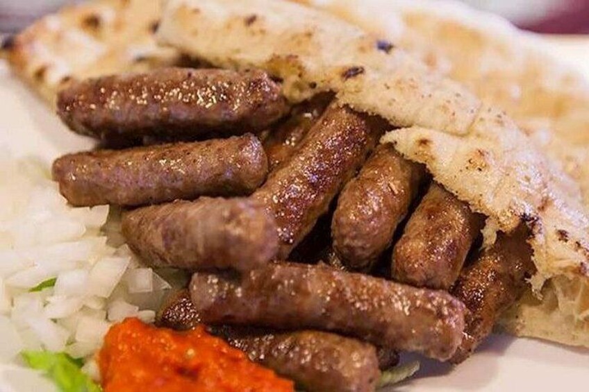 A plate with grilled sausages, rice, and a piece of flatbread. 5