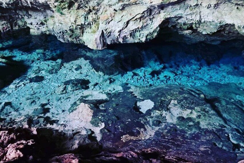 A cave with clear blue water and rocky formations. 4