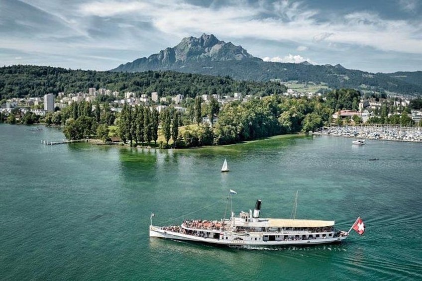 A riverboat with passengers, a mountainous landscape, and a town in the background. 5