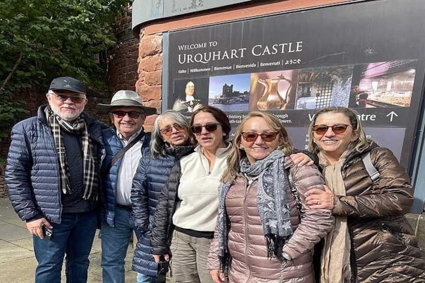 Un groupe de personnes posant devant un panneau sur lequel on peut lire : « Bienvenue au château d’Urquhart. » 1