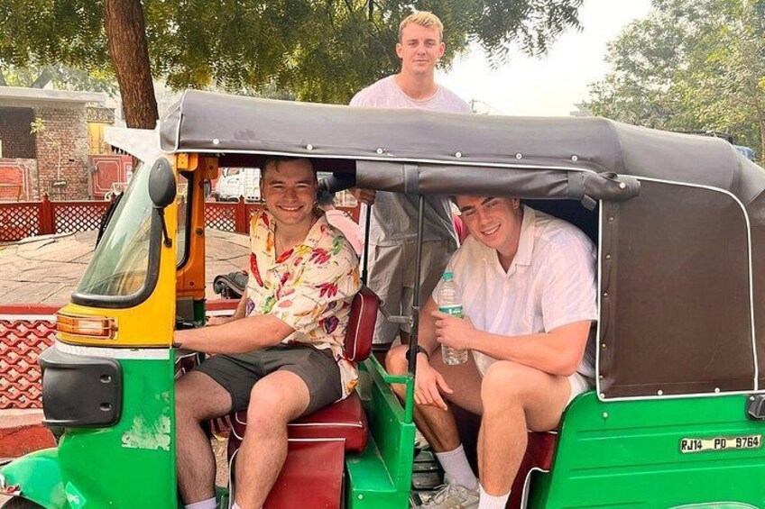 Trois personnes à bord d’un tuk-tuk vert. 1