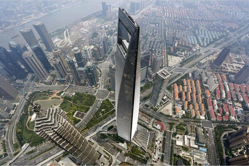 A modern skyscraper with a unique design, surrounded by a dense urban area with various buildings and roads. 3