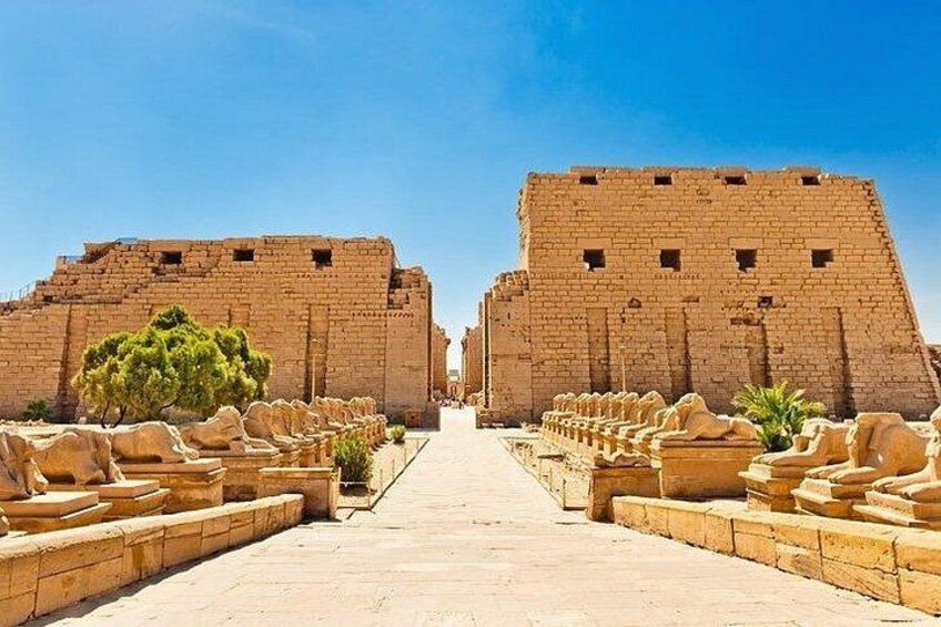 A pathway leading to a large ancient structure with a clear sky above. 5
