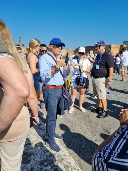 A group of people standing outdoors, some holding water bottles, with a clear sky in the background. 1