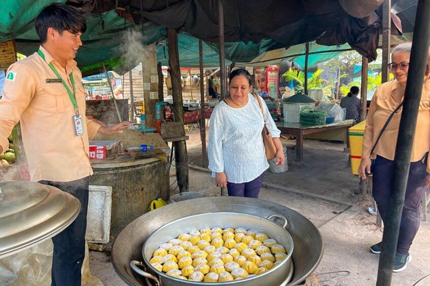 A street food vendor cooking corn on the cob, a large metal bowl of corn, and a market stall with various items. 5