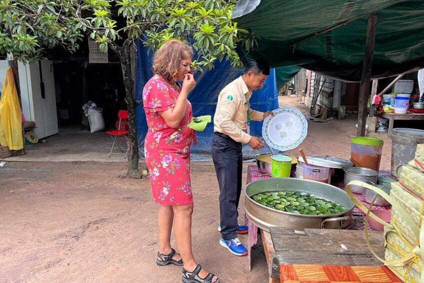 A woman in a floral dress and a man in a shirt and pants preparing food outdoors. 4