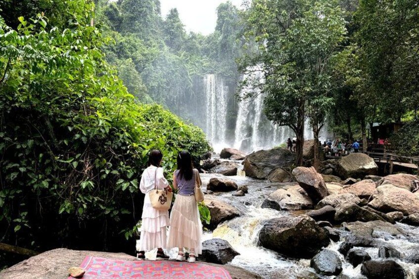 A waterfall surrounded by lush greenery and rocks. 1