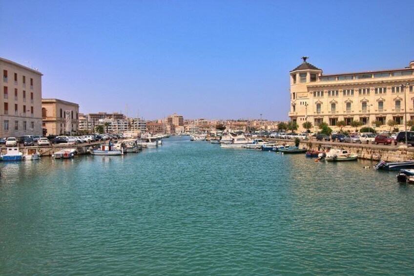 A marina with boats docked, buildings, and a clear sky. 2