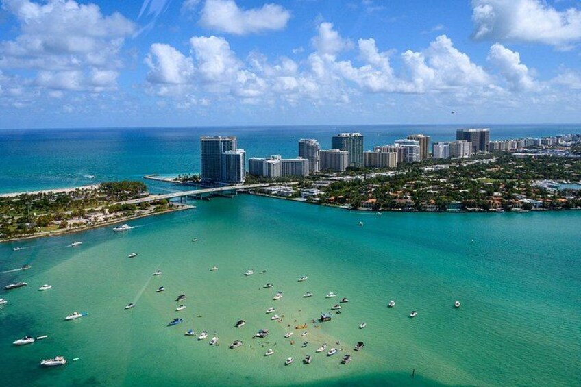 A coastal cityscape with a marina filled with boats, a clear blue sky, and a large body of water. 2