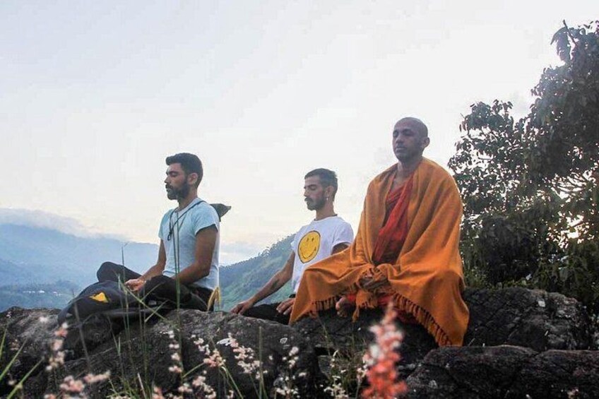 Three individuals sitting on rocks with a mountainous landscape in the background. 4
