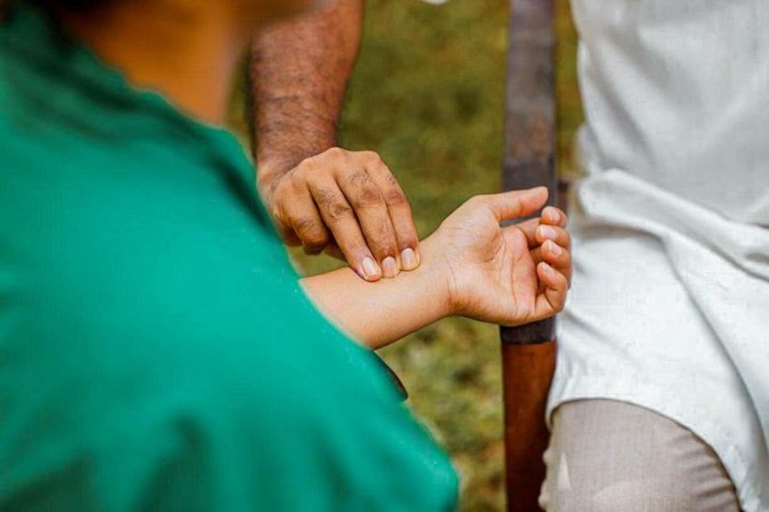 Eine Person in einem grünen Hemd misst den Handgelenkumfang einer anderen Person. 4