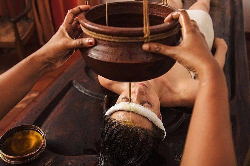 Eine Person erhält eine heiße Steinmassage, neben ihr Schalen mit Öl und Wasser. 3