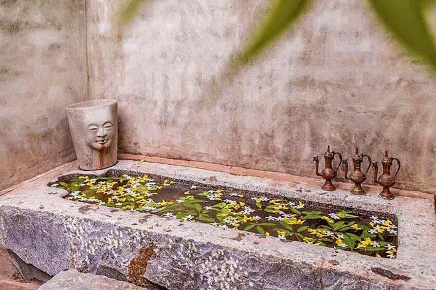 Ein Steinebecken mit Blumen und einer Steinkopfskulptur. 5